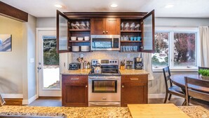A modern kitchen with a built-in oven, microwave, and gas stove. It features wooden cabinets and a granite countertop. - Spacious, Modern 4BR house with city view and easy access to ski resorts (Salt Lake City)