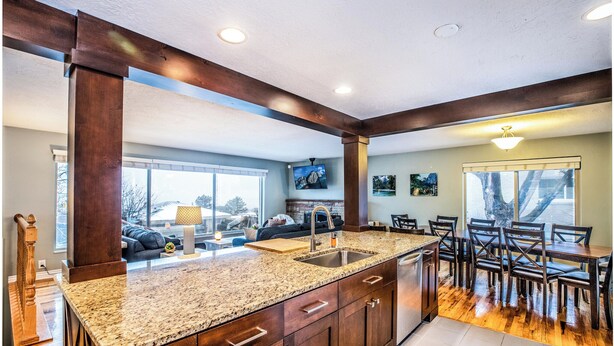 A kitchen with a granite countertop, wooden cabinets, a large island with a sink, and a dining area with wooden chairs and a table. - Spacious, Modern 4BR house with city view and easy access to ski resorts (Salt Lake City)