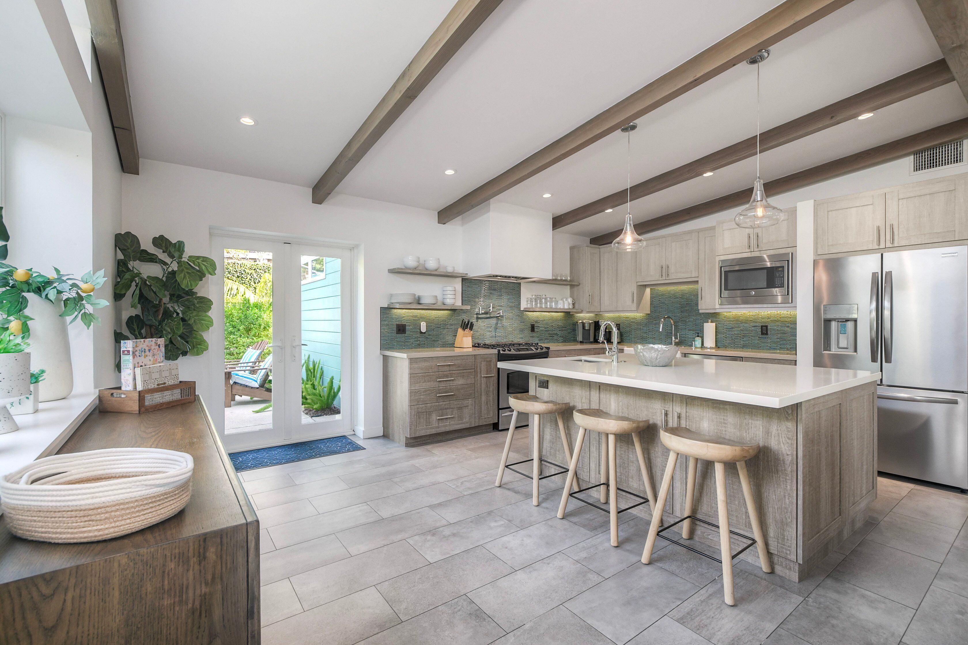 Una cucina moderna con un'isola grande, sgabelli di legno ed elettrodomestici in acciaio inossidabile.