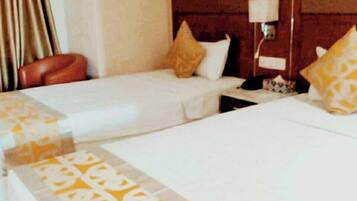 A hotel room with two beds, a wooden headboard, a nightstand, and a lamp.