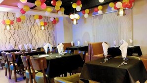 A restaurant with tables set for dining, balloons hanging from the ceiling, and patterned wallpaper on the walls. - Annex Suites Bogura (Bogra)