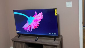 En platt-TV står på ett träställ mot en vägg.