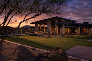 A modern building with stone pillars, outdoor seating, and a well-maintained lawn. - Sierra Vista - Gated Community in Sereno Canyon (Scottsdale)