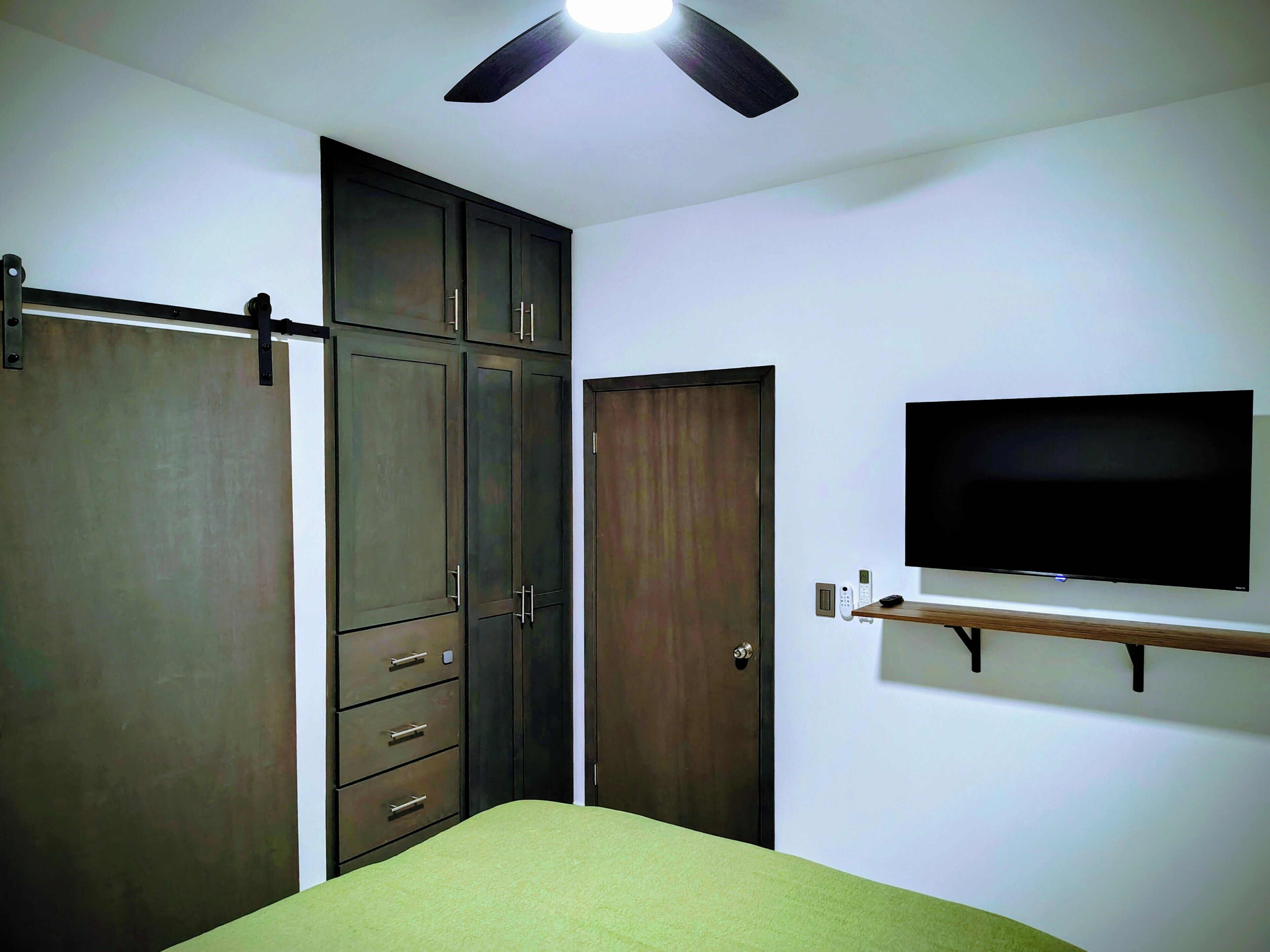 A bedroom with a bed, wardrobe, and a mounted TV.