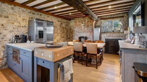 Una cocina rústica con paredes de piedra, techo de madera y chimenea de piedra.