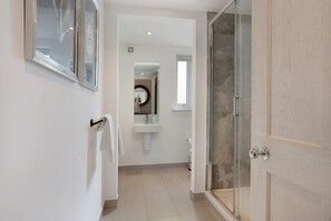 A modern bathroom with a glass shower enclosure, a sink with a mirror, and a towel rack.