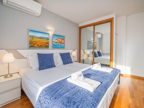 Une chambre d’hôtel avec un grand lit, deux tables de chevet, un miroir et deux tableaux accrochés au mur.