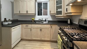 Une cuisine moderne avec des meubles de couleur bois clair, un évier en acier inoxydable et une cuisinière à gaz.