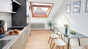 Une cuisine moderne dotée d’une verrière, d’une table à manger en bois et de chaises.