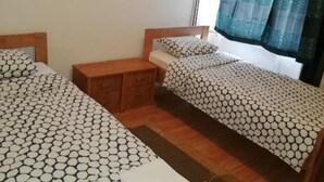 A room with two beds, a wooden nightstand, and a small table. - Lička Vodenica Rustical Oasis (Josipdol)