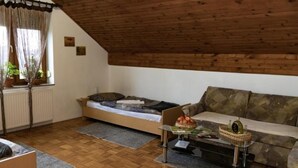 Une pièce de style loft avec un plafond en bois, un lit, un canapé et une petite table sur laquelle se trouve un panier de fruits.