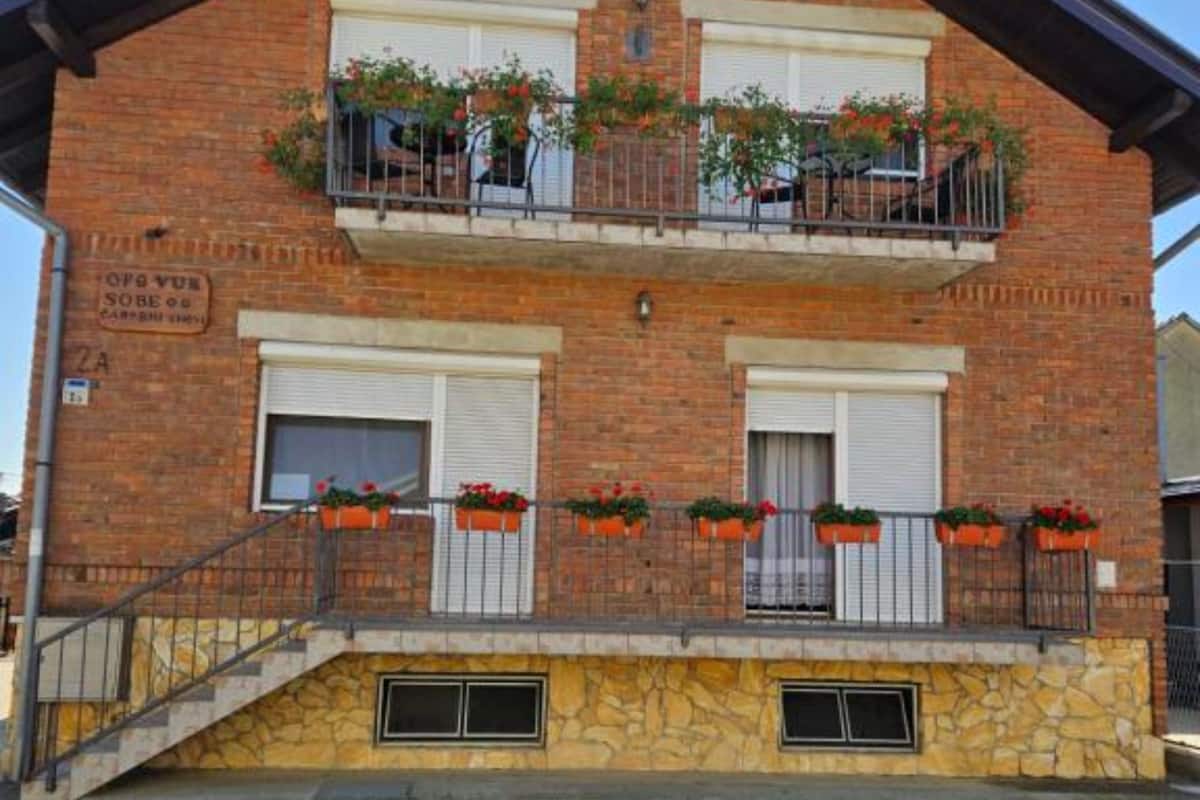 Ein zweistöckiges Gebäude mit steinernem Sockel, einem Balkon mit Blumenkästen und einem Schild, das 'SOBERO' ausweist.
