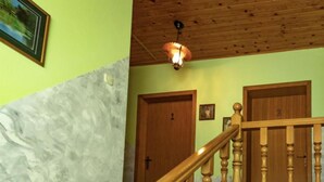 Un escalier avec des balustrades en bois mène à un palier où se trouvent deux portes en bois, dont l’une est marquée du numéro 1.