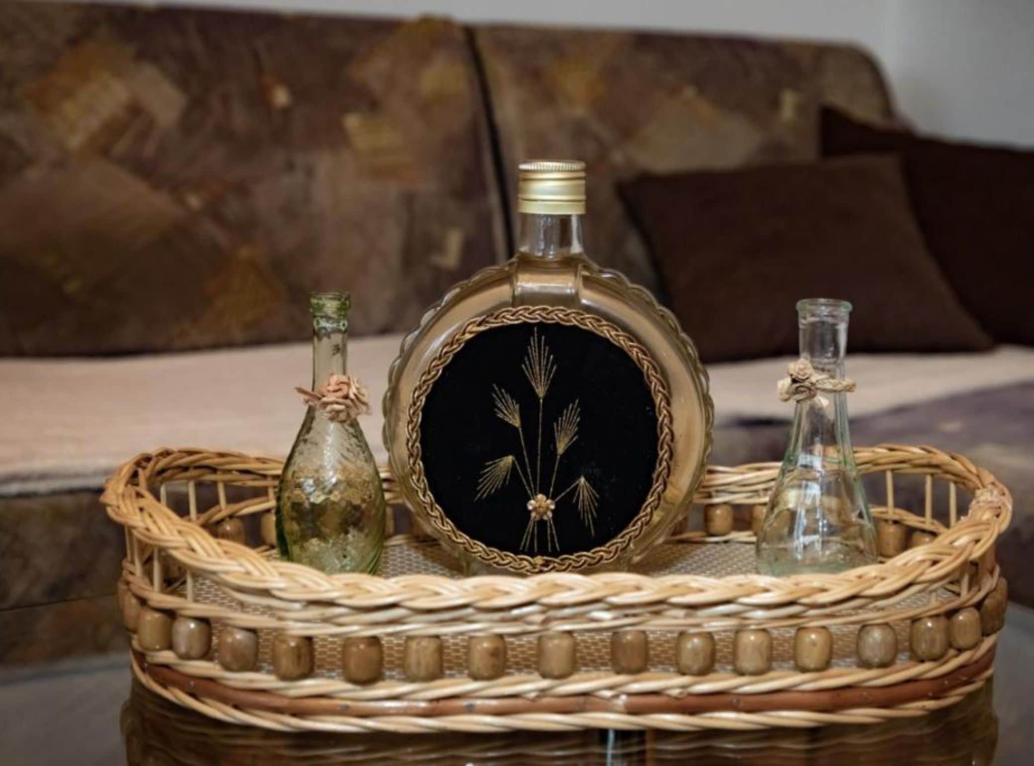 Una bandeja de mimbre con tres botellas de vidrio sobre una mesa.