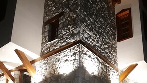 A stone building with a wooden roof and a white wall adjacent to it.