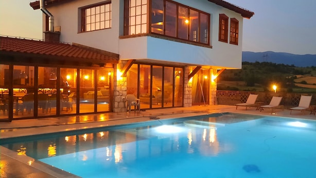 A two-story building with a swimming pool, outdoor seating, and a view of the mountains.