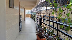 A corridor with tiled flooring, metal railings, and potted plants. - Great Samrat Residency (Khopoli)