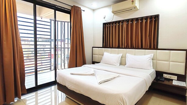 A hotel room with a bed, curtains, an air conditioning unit, and a view through a window. - Great Samrat Residency (Khopoli)