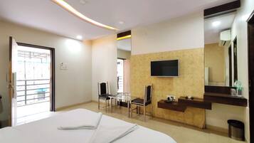 Habitación de hotel con cama, escritorio, silla, televisor montado en la pared y espejo.