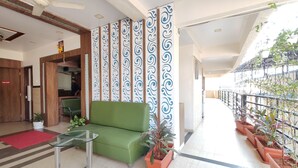 A hotel lobby with a green sofa, a glass table, decorative panels, and potted plants. - Great Samrat Residency (Khopoli)