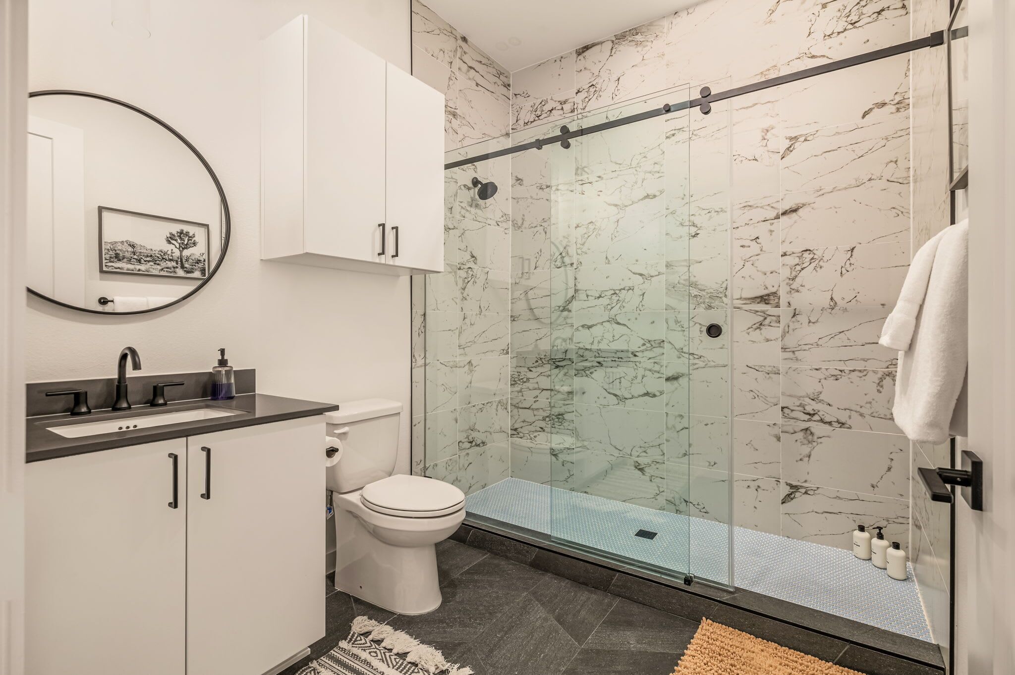 Une salle de bain moderne avec une douche en verre, des toilettes blanches et un lavabo avec un pare-éclaboussures en marbre.
