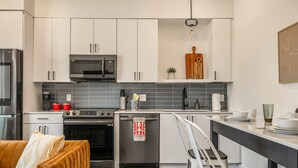 Una cocina moderna con armarios blancos, electrodomésticos de acero inoxidable y un backsplash de azulejos grises.