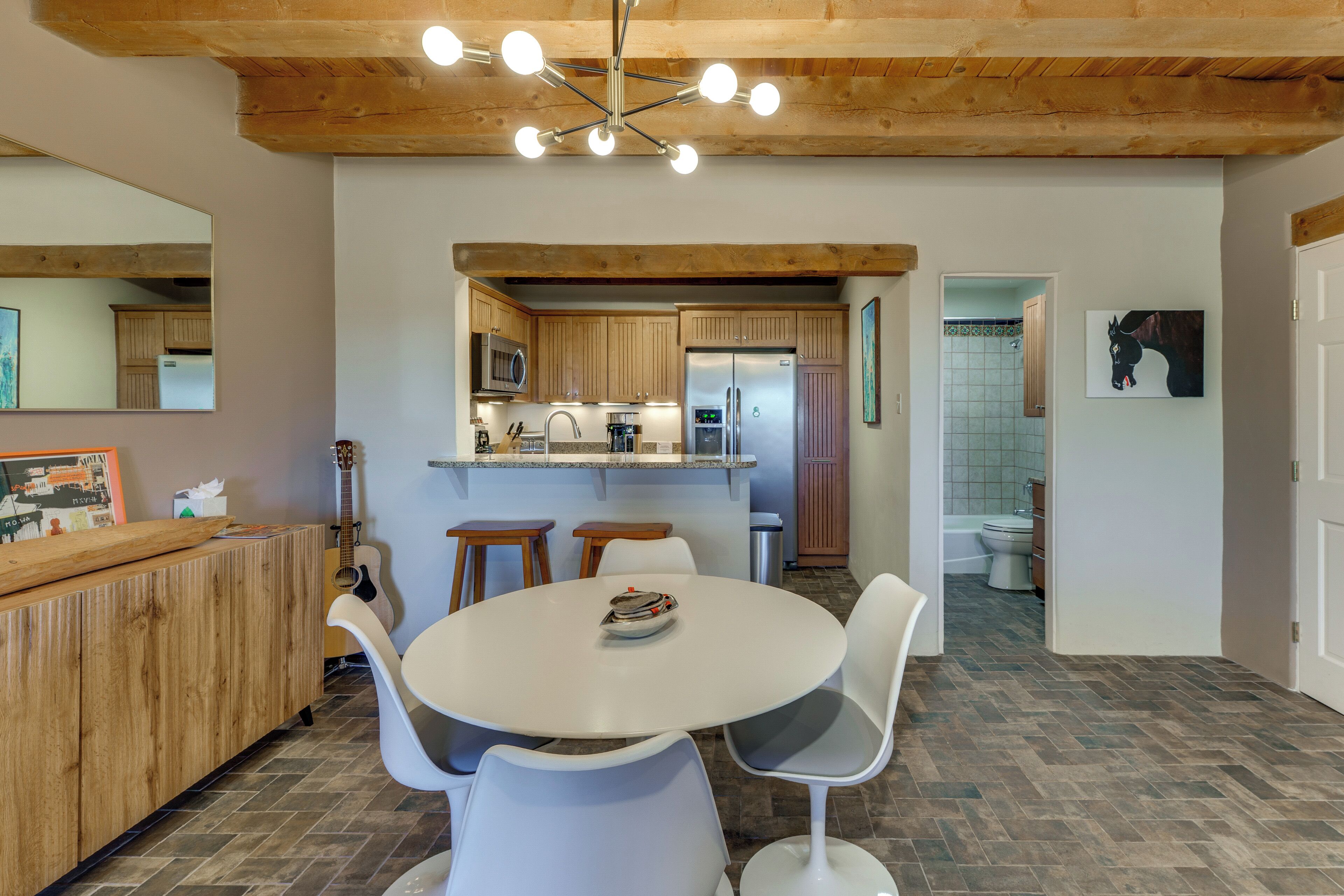 Een moderne keuken met houten kastjes, een centraal eiland en een eethoek met witte stoelen.