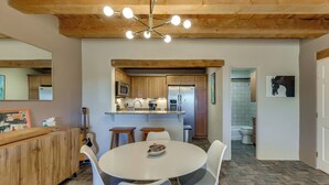 A modern kitchen with wooden cabinets, a central island, and a dining area with white chairs. - Ski, Hike & Fish! Beautiful Retreat Near Taos (Valdez)