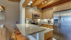 A modern kitchen with granite countertops, wooden cabinets, stainless steel appliances, and a built-in bar area. - Ski, Hike & Fish! Beautiful Retreat Near Taos (Valdez)