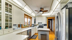 Una cocina moderna con armarios blancos, electrodomésticos de acero inoxidable y suelo de madera.