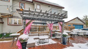 Un espacio cubierto con mobiliario exterior, una pérgola de madera y suelo de ladrillo.