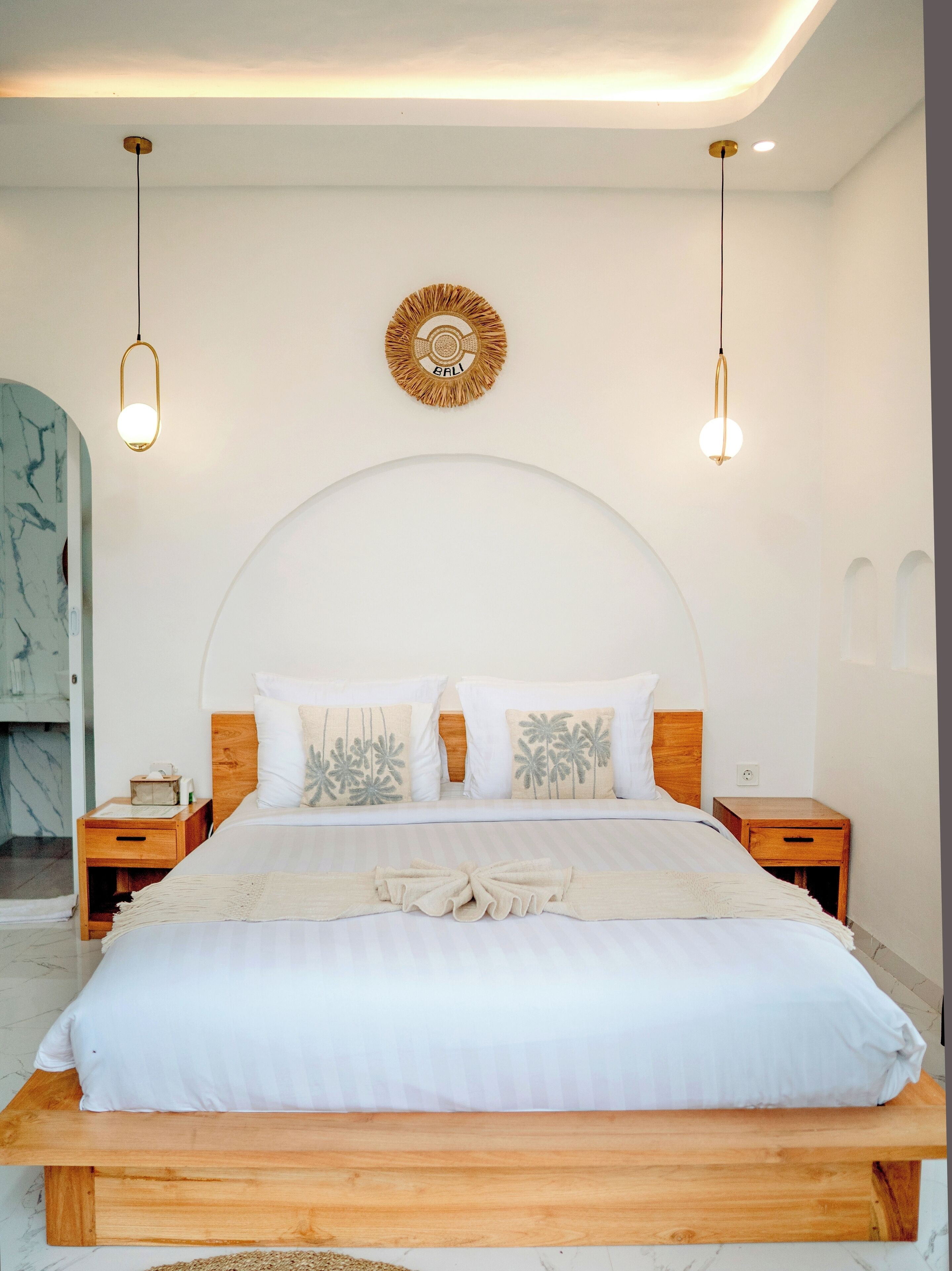 Ein modernes Schlafzimmer mit einem großen Bett, einem Holz-Kopfteil, zwei Nachttischen und einer Wandleuchte.
