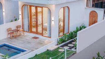 A modern house with a swimming pool, a dining area with wooden furniture, and a garden with plants and stepping stones.