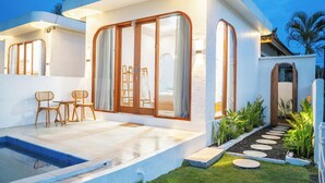 Ein modernes Haus mit Swimmingpool, Holzmöbeln und einem Garten mit trittfesten Steinen.