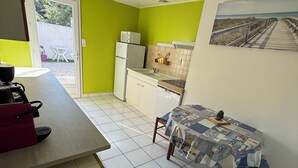 Eine kompakte Küche mit Essbereich, einem Kühlschrank, einer Mikrowelle und einem Fliesenboden.