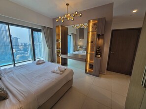 Une chambre d’hôtel moderne avec un grand lit, une coiffeuse avec un miroir et une vue sur la ville.