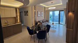 A modern living room with a dining area, a kitchen, and a large window offering a city view. - Royale Highend  Burj and Fountain View (Dubai)
