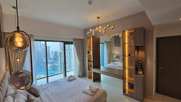 A modern hotel room with a large bed, a vanity with a mirror, and a city view. - Royale Highend  Burj and Fountain View (Dubai)