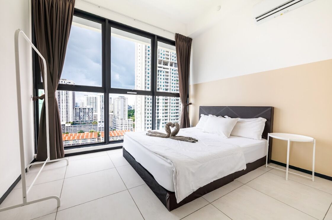 A hotel room with a large bed, a small bedside table, and a view of high-rise buildings.
