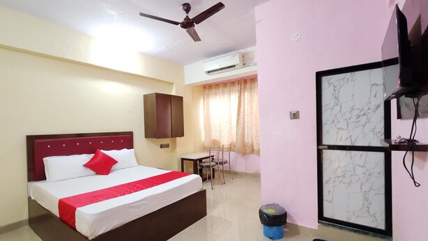 A hotel room with a bed, a desk, a chair, a ceiling fan, an air conditioning unit, and a television on the wall. - Hotel Pallavi Inn (Panvel)