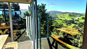 A balcony with a view of a green valley and hills.