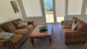 Una sala de estar con dos sofás marrones, una mesa de centro de madera y cojines estampados.