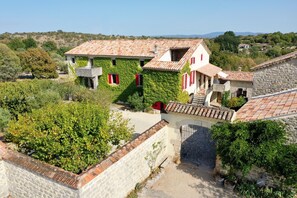 Un bâtiment traditionnel en pierre, avec un toit en tuiles, des murs couverts de lierre et un petit balcon.
