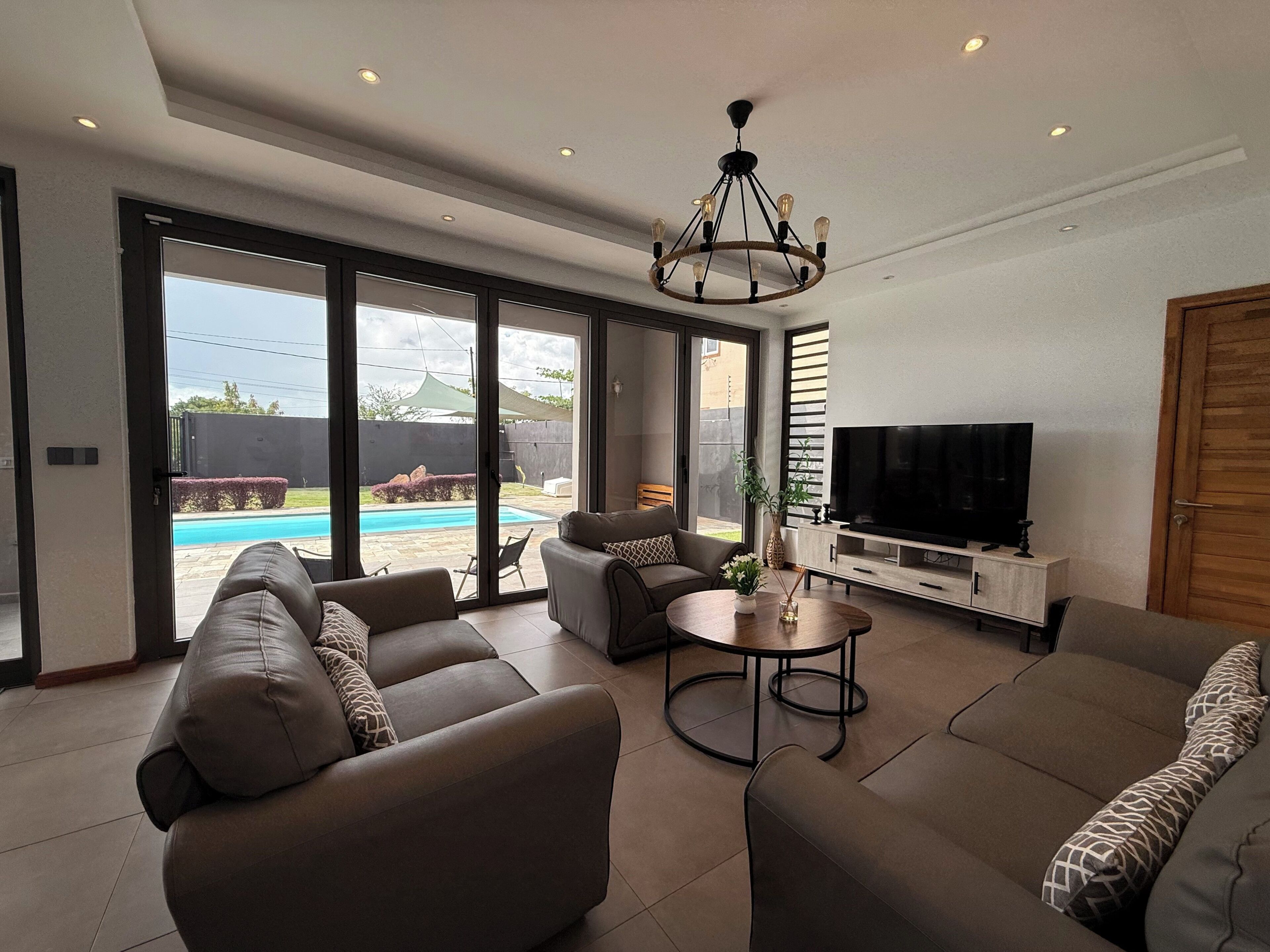 A modern living room with a sofa set, a TV, and a dining table.