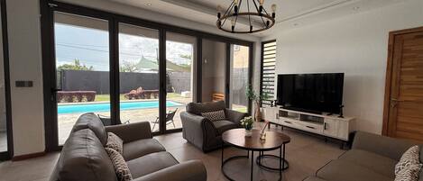 A modern living room with a sofa set, a TV, and a dining table.