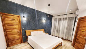 A bedroom with a wooden bed, a dark blue accent wall, and a wooden wardrobe. - Tropical Elegance Haven - 4 bedrooms Villa on Mauritius’ Northwest Coast (Tombeau Bay)