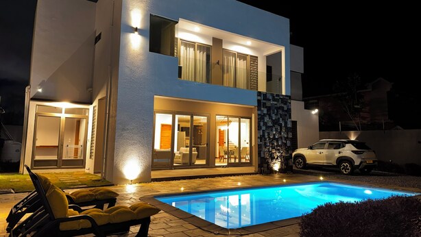 A modern two-story house with a swimming pool, outdoor seating, and a white car parked nearby. - Tropical Elegance Haven - 4 bedrooms Villa on Mauritius’ Northwest Coast (Tombeau Bay)