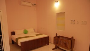 A bedroom with a wooden bed, a green pillow, a bedside table, a wooden bench, and a wall-mounted air conditioner. - Kpp Resort (Kalkulam)