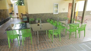 A dining area with a glass table and green chairs, a staircase in the background, and a tiled floor. - Kpp Resort (Kalkulam)