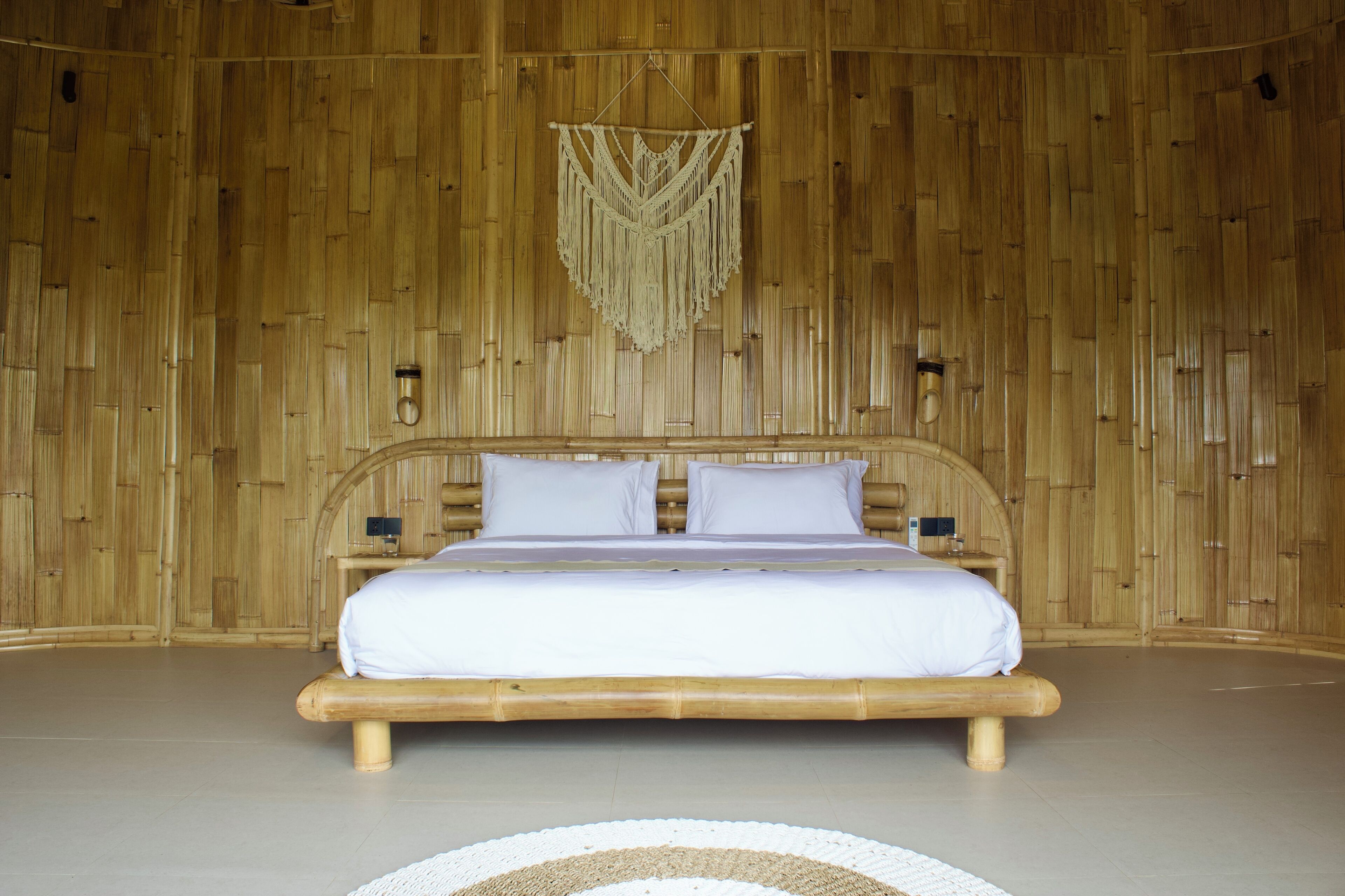 Une chambre avec un grand lit, des murs en bois et une décoration murale en macramé.